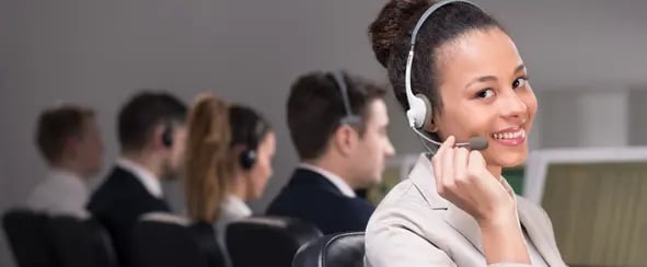 a young lady sat in a call centre with a headset on smiling